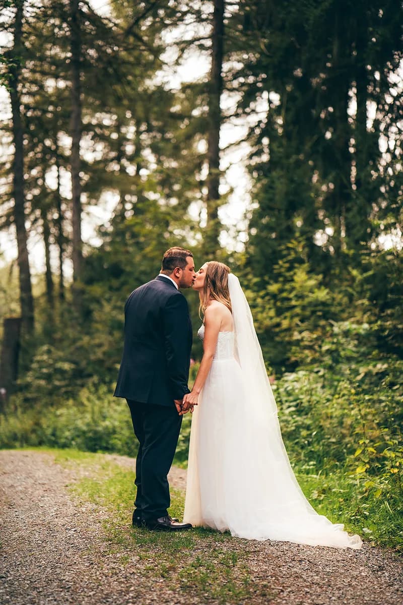 Brautpaar küsst sich auf einem Waldweg — Hochzeitsfotografie Lara & Denis bei Bernstein