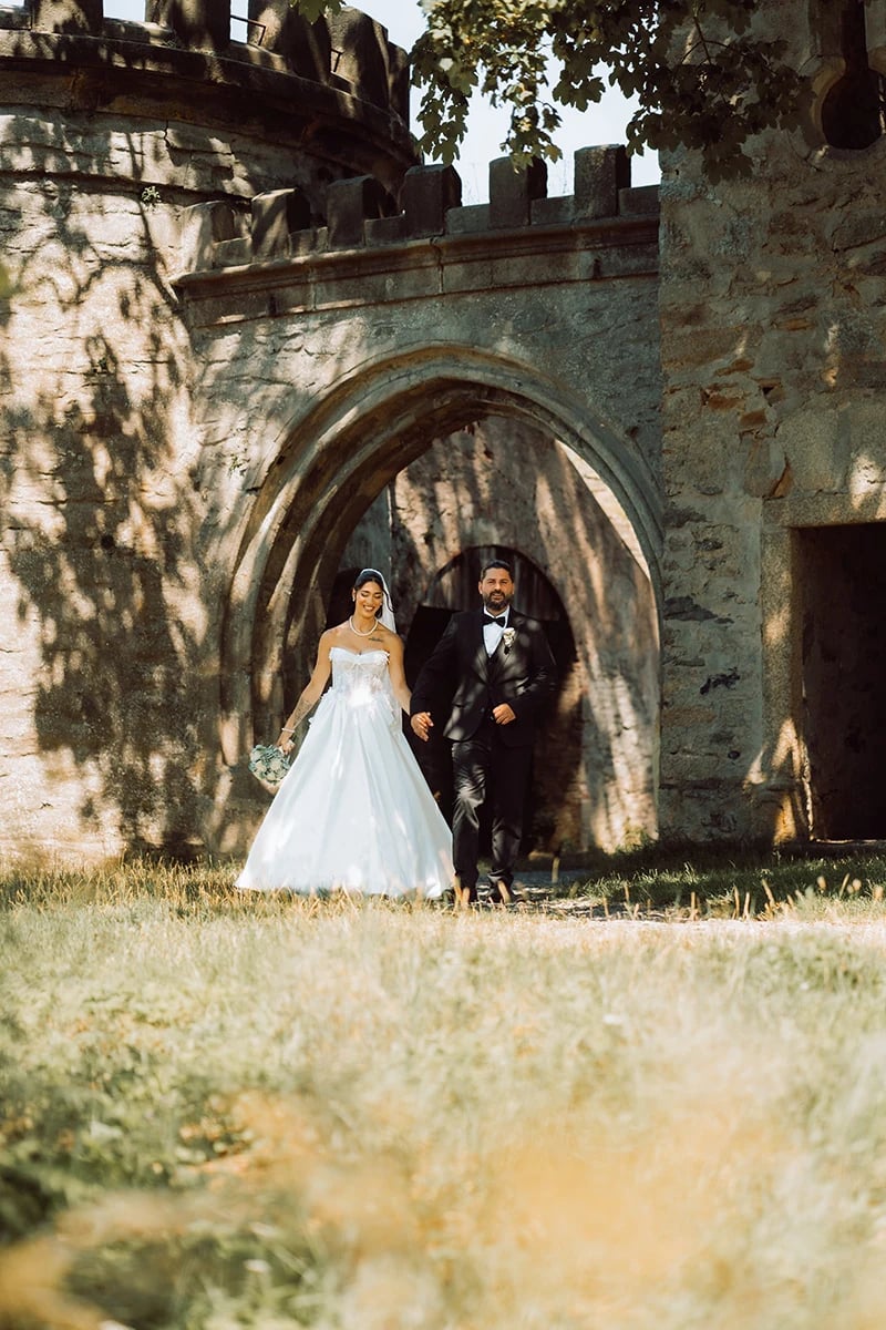 Brautpaar tritt Hand in Hand aus dem Burgtor der Ruine — Hochzeit Elisabete & Nafi am Theresienstein in Hof