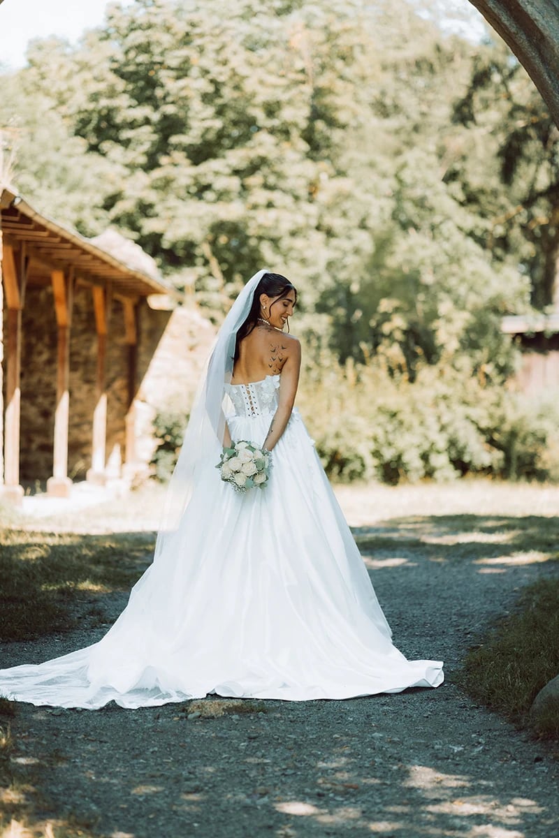 Braut von hinten mit ausgebreiteter Schleppe und Schleier — Brautkleid-Detail beim Shooting am Theresienstein