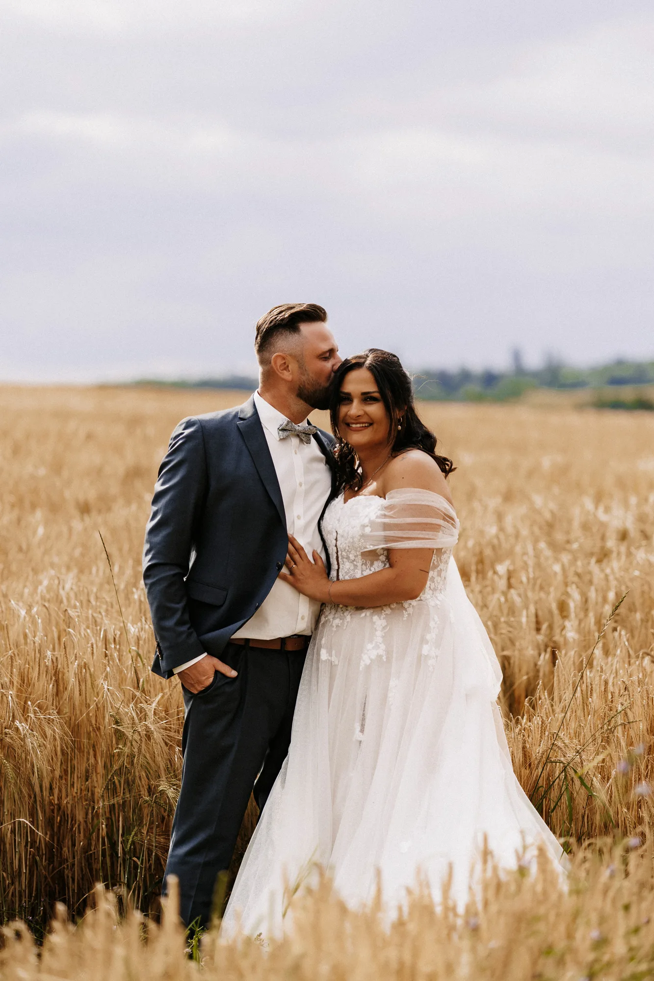 Bräutigam küsst die Braut im goldenen Kornfeld auf die Stirn — Hochzeit Jacqueline & Sascha in Berg, Oberfranken