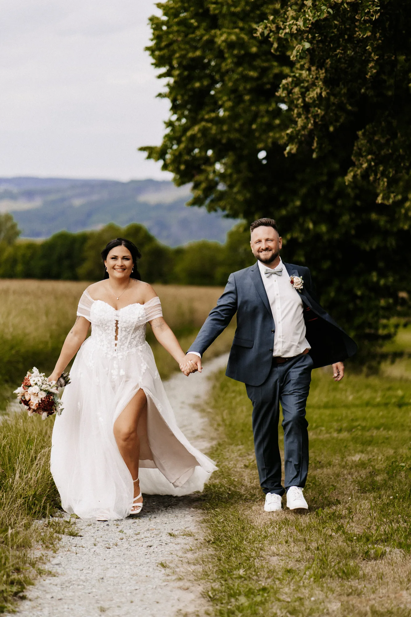 Brautpaar spaziert Hand in Hand über einen Feldweg — Hochzeitsfotograf Oberfranken, Jacqueline & Sascha